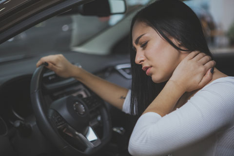Women in car holding neck in pain